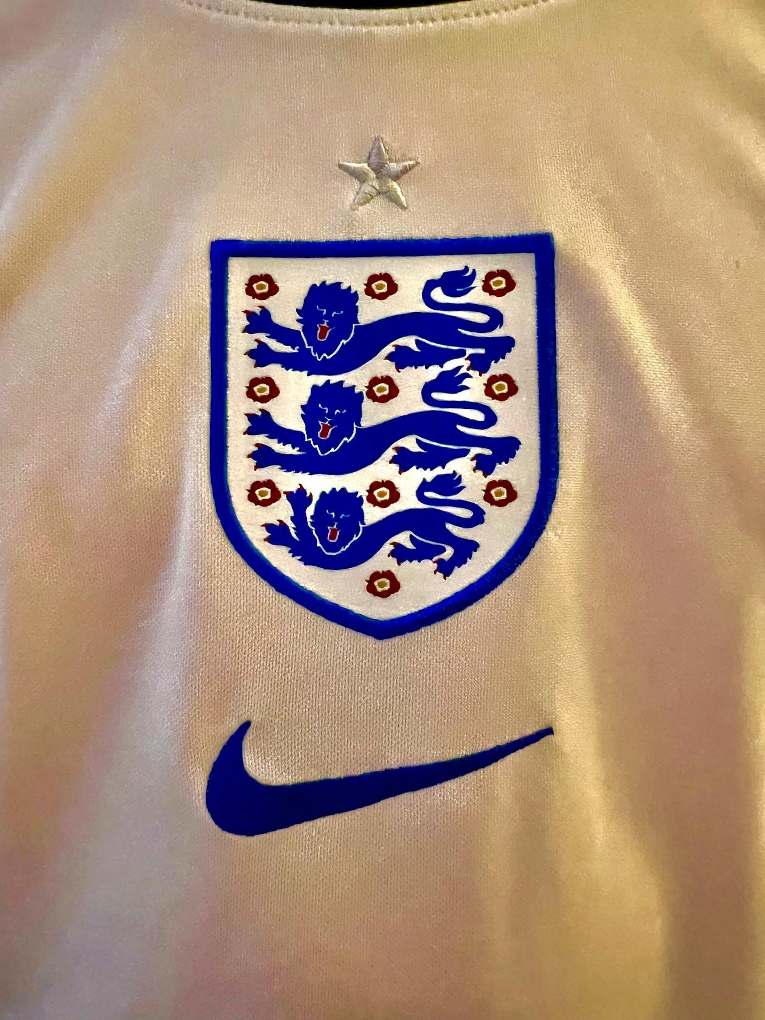 Close-up of an England football jersey emblem highlighting the iconic three lions badge.