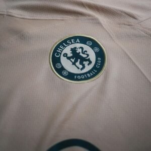 Close-up view of Chelsea Football Club logo on a beige t-shirt, ideal for sports and fashion themes.