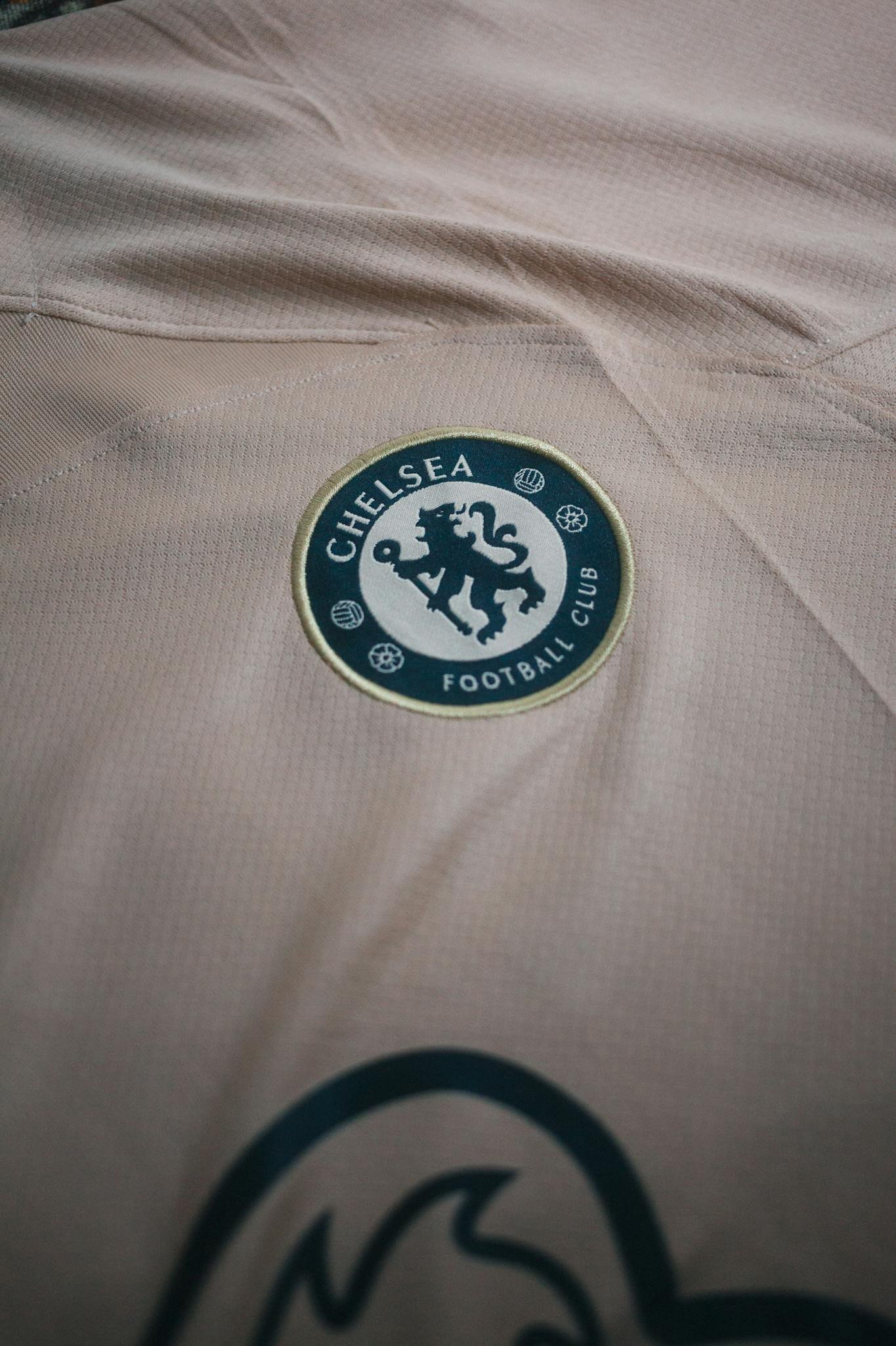 Close-up view of Chelsea Football Club logo on a beige t-shirt, ideal for sports and fashion themes.