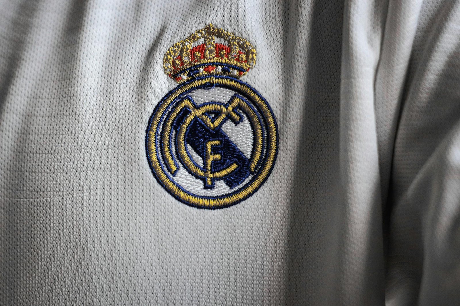 Detailed view of a famous embroidered logo on a white sports jersey fabric.